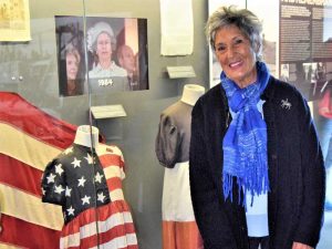 Danièle Patrix standing in front of the iconic American flag dress that she wore as a little girl