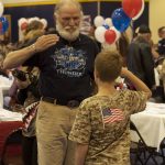 An older veteran saluting a young boy who is saluting him back