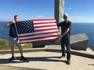 Guest author for The Girl Who Wore Freedom Douglas Bond holding an American flag in Normandy