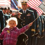 A young girl waves a US flag in a Veterans day parade in NYC