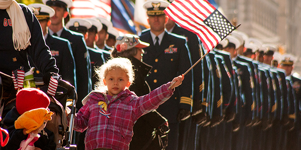 A young girl waves a US flag in a Veterans day parade in NYC