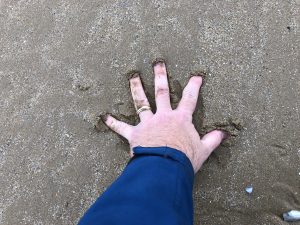 Jeff Kurtenacker, lead composer on The Girl Who Wore Freedom, putting his hand in the sands of Normandy