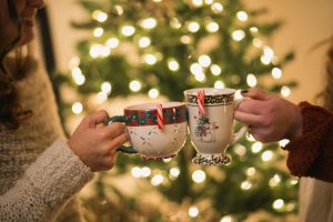 Two women holding Christmas mugs with candy canes hanging out of them