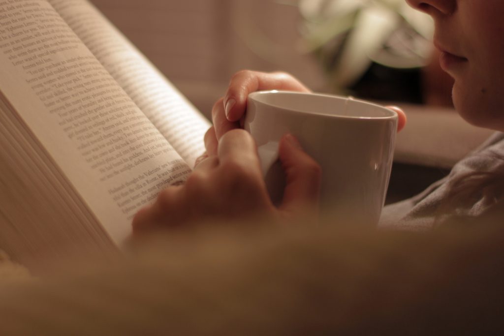 Woman reading a book sipping a warm beverage