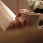 Woman reading a book sipping a warm beverage