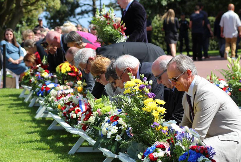 People laying flowers at a memorial in Normandy